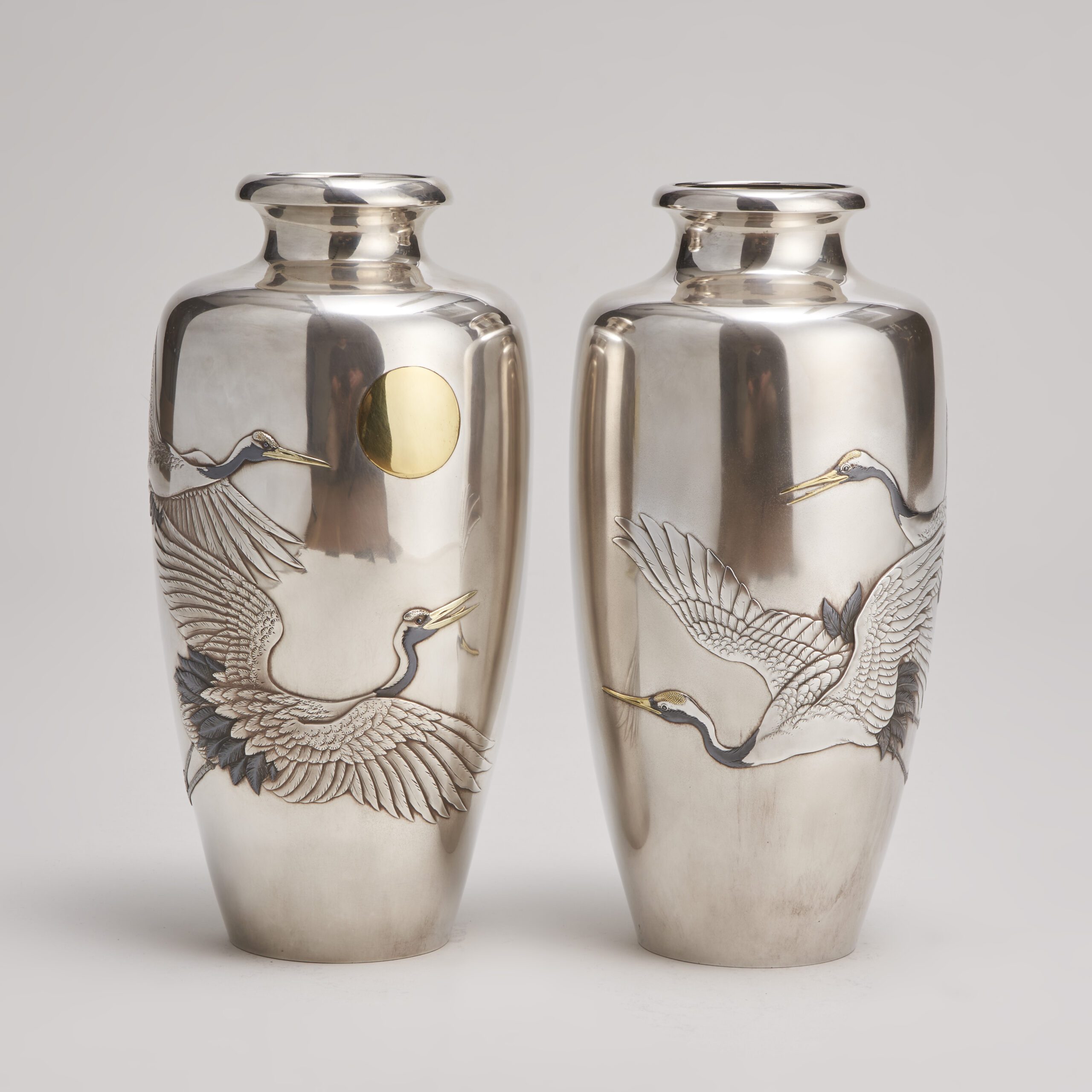 A stylish pair of Japanese silver vases depicting flying cranes 
